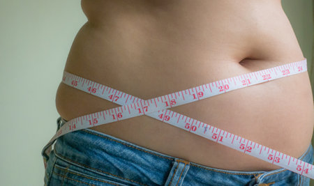 Fat woman measuring her waist with a tape measure, weight loss conceptの写真素材