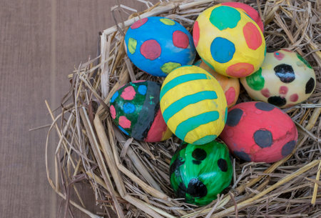 Painted Easter eggs in a nest of hay on a wooden background