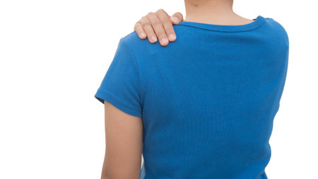 Man in blue t-shirt with pain in his back isolated on white backgroundの写真素材