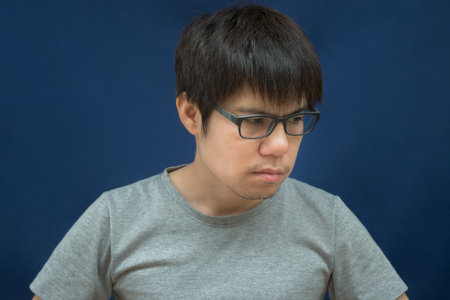 Portrait of young asian man with glasses on blue background.の写真素材