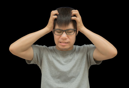 Young asian man with headache and stress, isolated on black backgroundの写真素材