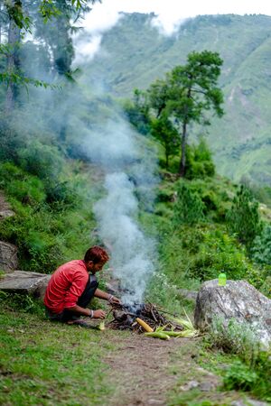 Kullu, Himachal Pradesh, India - September 03, 2018 : Grilling Corn on Bonfire in Himalayas, India