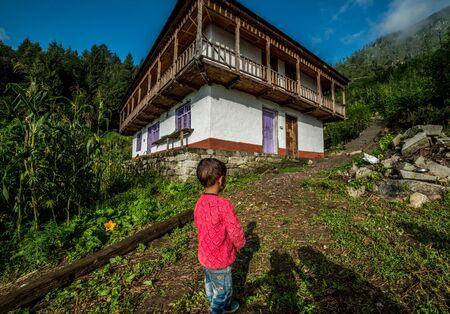 Kullu, Himachal Pradesh, India - September 01, 2018 : boy standing in front of his traditional wooden house in mountain, Indiaのeditorial素材