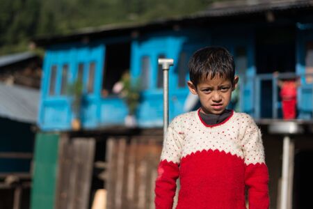 Kullu, Himachal Pradesh, India - September 01, 2018 : Himalayan boy standing in front of his traditional wooden house in mountain, Indiaのeditorial素材