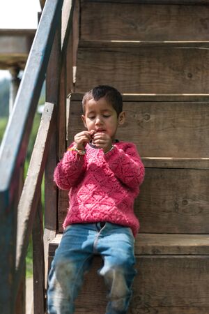 Kullu, Himachal Pradesh, India - September 01, 2018 : Himalayan kid at Stairs of traditional wooden house in mountain Indiaのeditorial素材