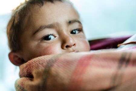Kullu, Himachal Pradesh, India - December 21, 2018 : closeup of a poor staring hungry indian boy with sad expression on his face and his face and clothes are dirtyのeditorial素材