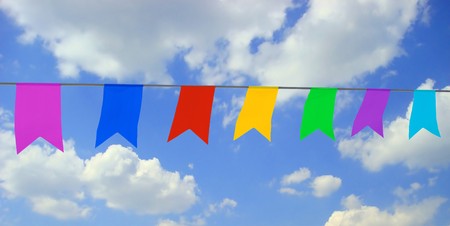 multi-colored garland on blue sky with white cloudsの写真素材