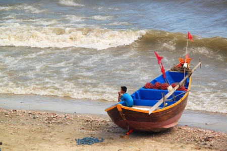 Mui Ne, Vietnam - May 8, 2011: Vietnamese boy seating in fishing boatのeditorial素材
