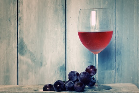 Photo of glass with pink wine and grapes