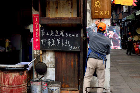 Man fixing up a poster by his street food stallのeditorial素材