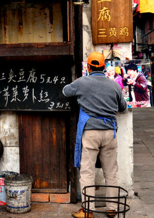 Man fixing up a poster by his street food stallのeditorial素材