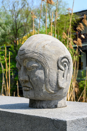 Stone head of Buddha in the garden, closeup of photo.の写真素材