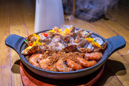 Seafood paella in a cast-iron pan on a wooden tableの写真素材