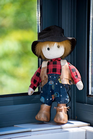 Wooden doll with hat and plaid shirt on the windowsillの写真素材