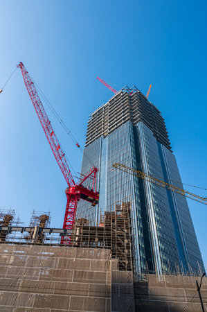 Construction site with cranes and building under construction against blue sky.