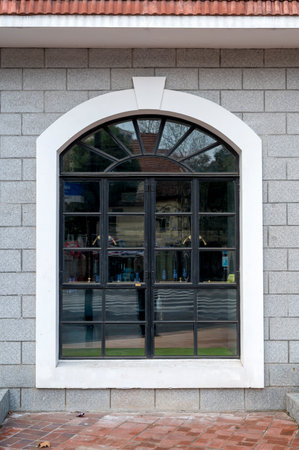 Window of a house with a stone wall and a decorative arch.
