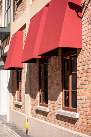 Facade of a modern building with red shutters and balcony.