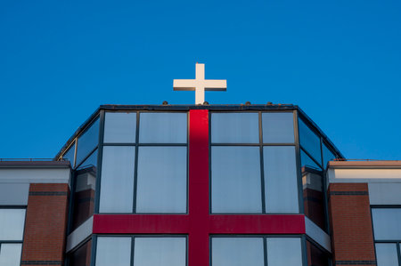 Cross on the facade of a modern building against the blue sky.の写真素材