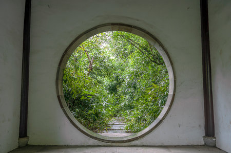 Round window with bamboo and green leaves in the garden, stock photoの写真素材