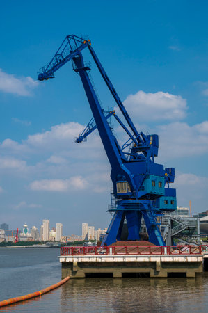 Port cargo crane on the background of the cityscape and blue skyの写真素材