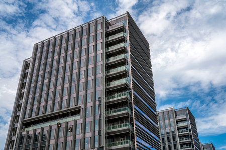 Modern high rise building with blue sky and white clouds in the background