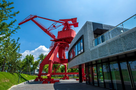 Modern red crane on a background of blue sky and green trees.の写真素材
