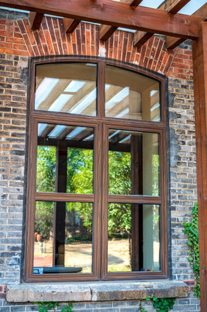 Wooden window on brick wall in modern house with green garden.