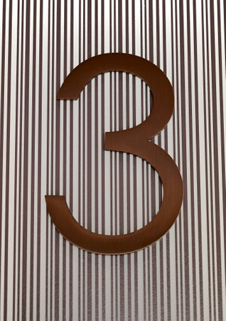 Wooden number three on a background of striped wall with vertical stripesの写真素材