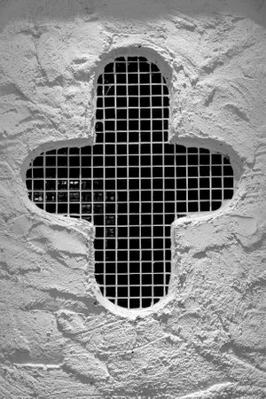 Black and white image of a cross on a white wall with a latticeの写真素材