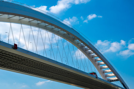 Pedestrian bridge over the river against the blue sky with clouds