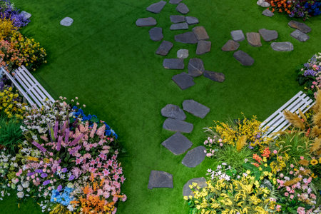 Colorful flower garden in the springtime with green grass and stones.