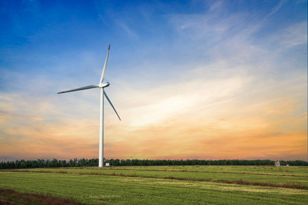 Wind turbine on the field with sunset sky background. Alternative energy source
