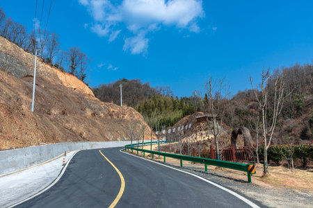 Asphalt road in the mountains under blue sky with white clouds.の写真素材