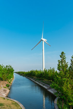 Wind turbine on the river bank with clear blue sky in sunny dayの写真素材