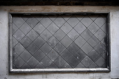 Old grunge metal window with black frame on the white wall.