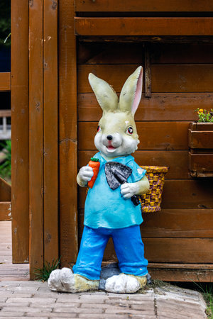 Easter bunny with basket of carrots in front of the wooden house