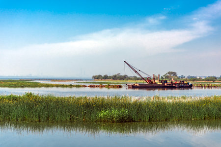 Barge on the river with reeds on a background of blue sky