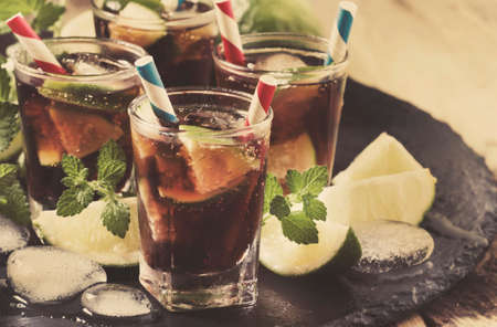 Cuba Libre alcoholic summer cocktail with lime, rum, mint and ice in a glass, selective focusの写真素材