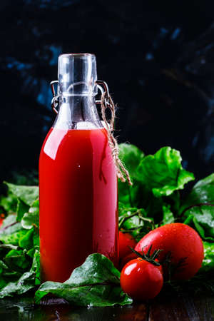 Vegetable juice from tomatoes, cucumbers, beets and spicy herbs in a bottle, low key, selective focusの写真素材