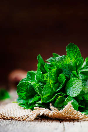 Fresh mint in a bundle, vintage wooden background, selective focus