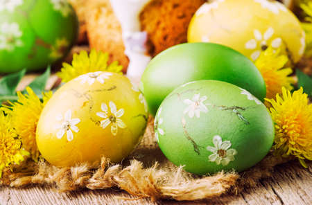 Easter green and yellow painted eggs, white apricot flowers, spring festive composition in rustic style, russian orthodox tradition, vintage wooden background, selective focusの写真素材