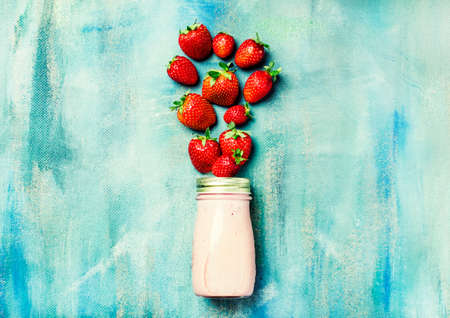 Strawberry smoothies in a bottle on a blue background, food background, flat layの写真素材