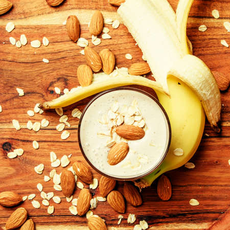Banana smoothie with oat flakes and almonds, vintage wooden tray, top viewの写真素材