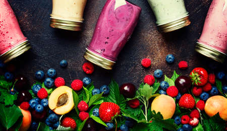 Healthy and useful colorful berry smoothies with yogurt, fresh fruit and raw berries on brown background, top viewの写真素材