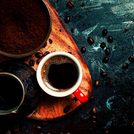 Ground coffee, Turkish coffee maker, cup with hot espresso on dark background, top view