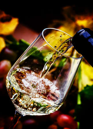 White wine being poured into a glass, vintage wood background, selective focusの写真素材