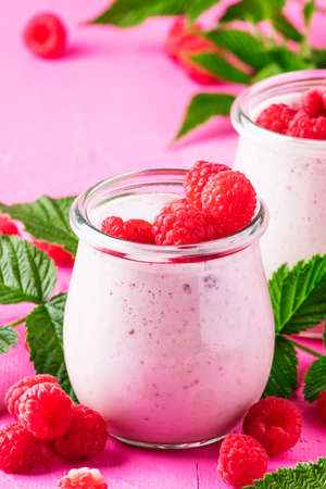 Raspberry smoothie with berry and yogurt on pink background, selective focus