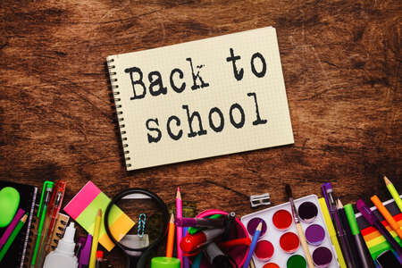 Back to school background with printed text, notebooks, pens, pencils, other stationery on wooden school desk, education concept, flat lay, top viewの写真素材