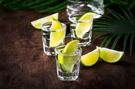 Cachaca - Brazilian strong alcoholic beverage from cane sugar, lime vodka, vintage wooden background, selective focusの写真素材
