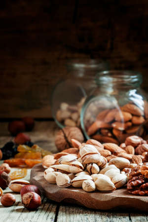 Nuts set of pistachios, walnuts, almonds and hazelnuts on a wooden background, selective focus